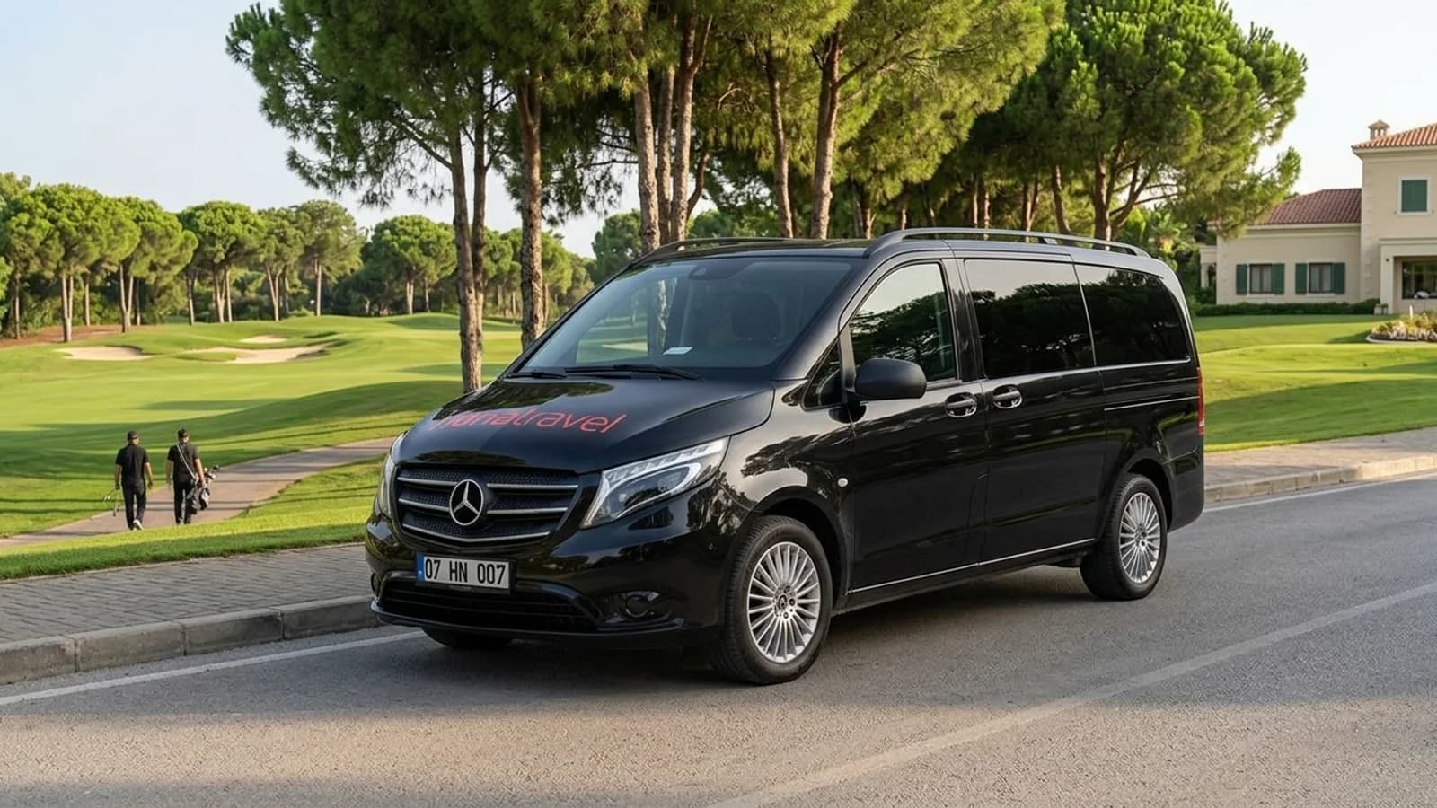 Things to Do in Belek: Beaches, Golf and Ancient Ruins A modern black transfer van stands parked on a quiet road beside a green Belek golf course.