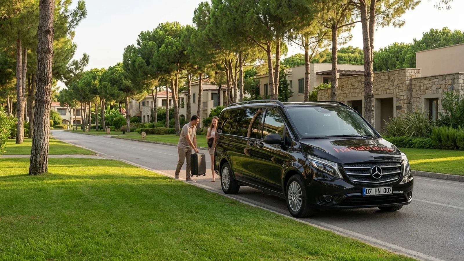 A sleek black transfer van stands parked on a quiet, pine-lined resort road in Belek.
