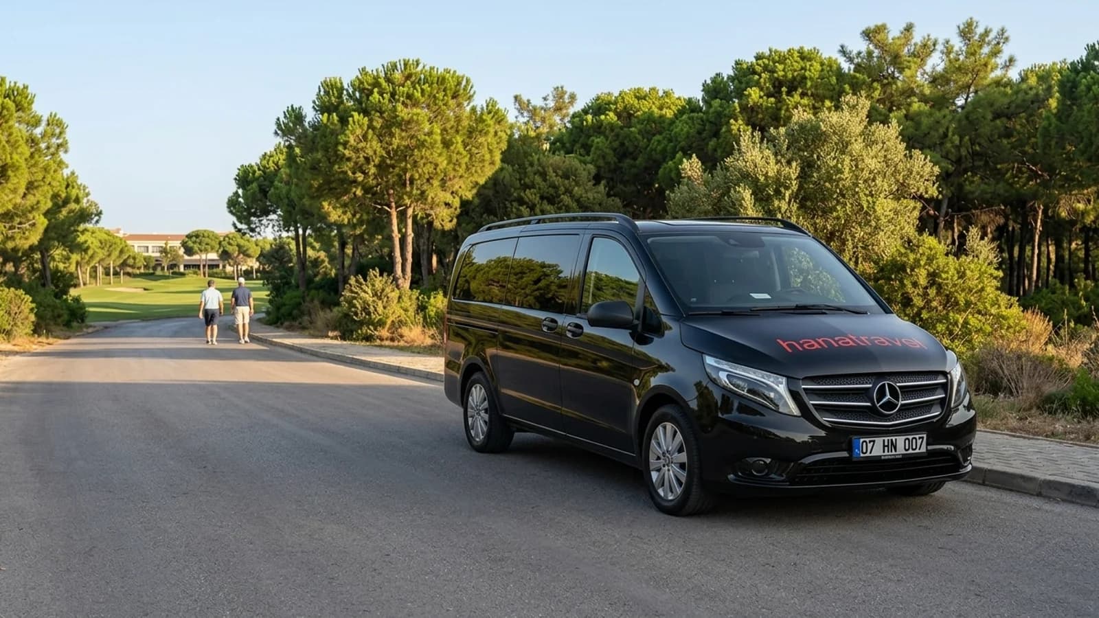 De juiste plek kiezen aan de kust van Belek A black transfer van stands on a flat asphalt road framed by pine trees near Belek.